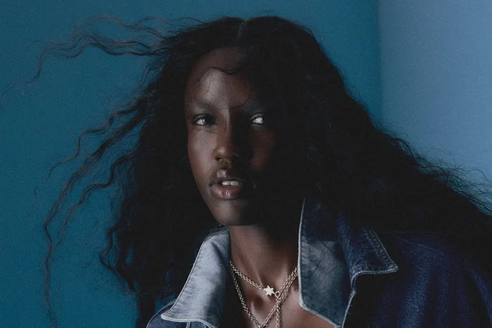 A model with long windswept hair in a denim jacket against a blue wall, from a LANE Casting shoot